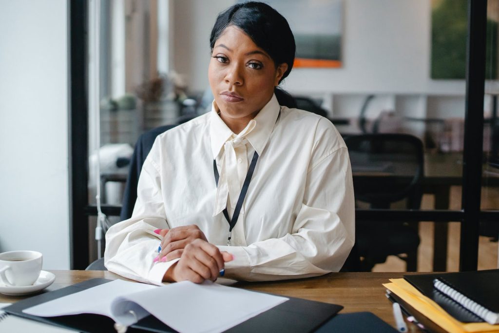 Serious black businesswoman sitting at desk in office